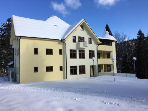 un gran edificio amarillo con nieve en el suelo en Penzión Probstner en Nová ľubovňa