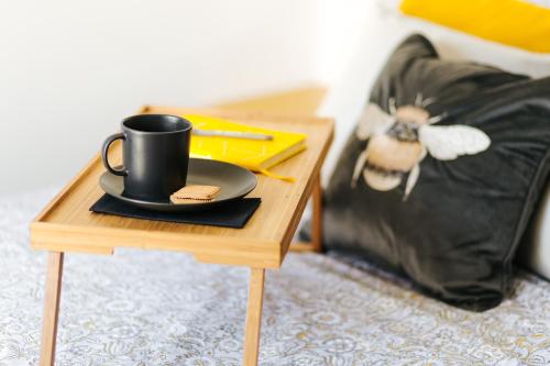 a table with a coffee cup on it next to a bed at Luxury Bumblebee Cottage Frome Longleat Aqua Sana Bath DOG FREEndly in Frome