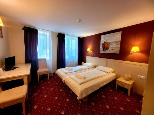 Habitación de hotel con 2 camas y escritorio en Hotel Pajurio vieskelis en Klaipėda