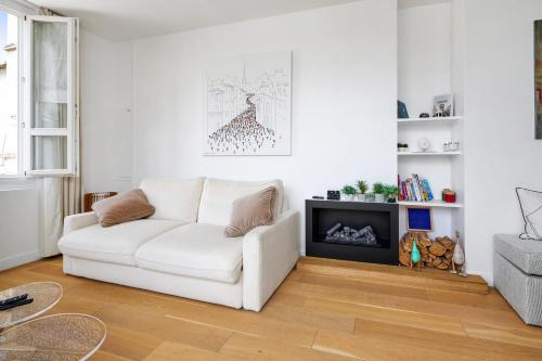a white living room with a white couch and a fireplace at Bright flat with balcony in the heart of the 7th arrondissement of Paris in Paris
