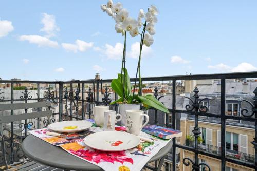 a table with plates and a vase of flowers on a balcony at Bright flat with balcony in the heart of the 7th arrondissement of Paris in Paris