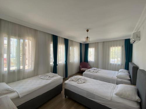 a room with three beds in a room with windows at Gülhan City Otel in Datca