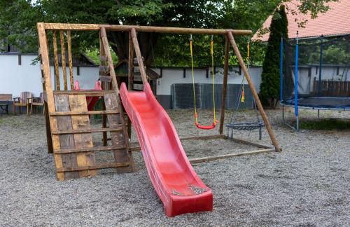 a playground with a red slide and a ladder at Pensiunea 7 Tei in Cisnadioara