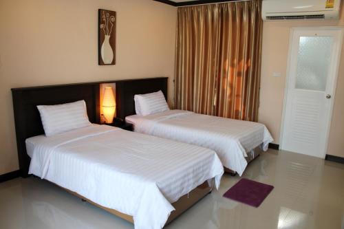 a bedroom with two beds and a lamp and a window at Triton Hotel Nakhonratchasima โรงแรมไททัน in Nakhon Ratchasima