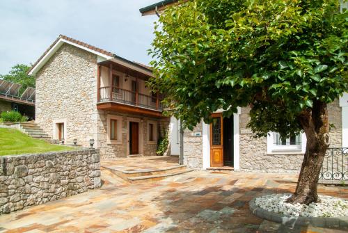una casa de piedra con un árbol delante en Casa vacacional Las Viñas, en Oviedo