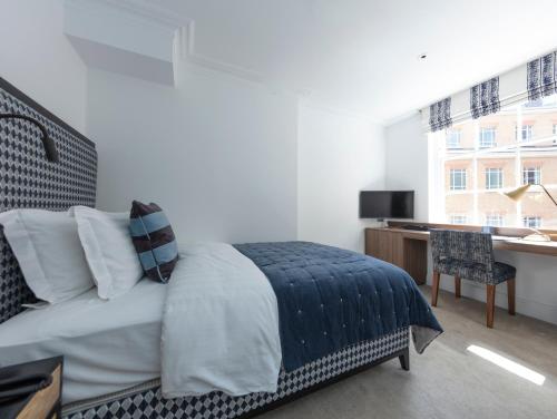 1 dormitorio con cama, escritorio y ventana en The City of London Club, en Londres