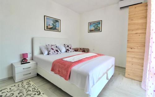 a white bedroom with a bed with a red blanket at Apartmani Kljajevic Sutomore in Bar