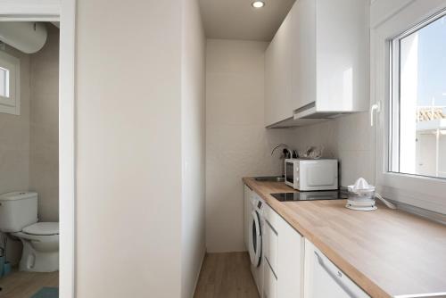 een witte keuken met een spoelbak en een magnetron bij Apartamento La Fuente in Vejer de la Frontera