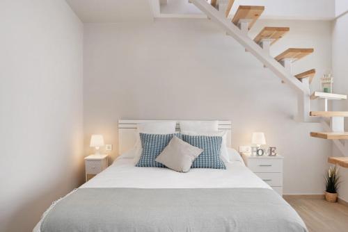 een witte slaapkamer met een bed met blauwe kussens bij Apartamento La Fuente in Vejer de la Frontera
