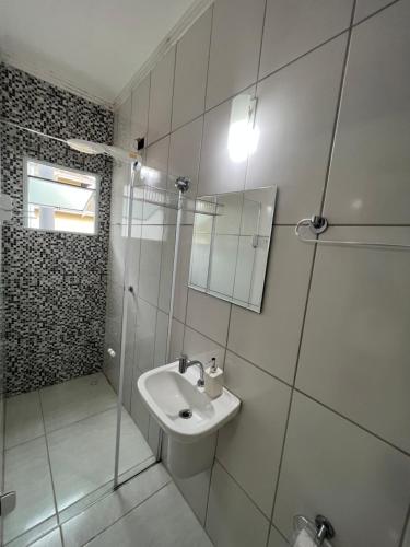 a white bathroom with a sink and a shower at Pura Vida Ubatuba Suítes in Ubatuba