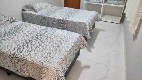 Wana casa 1 Requinte e conforto في ساو جوزيه دو ريو بريتو: سريرين جالسين على أرضية من البلاط في غرفة