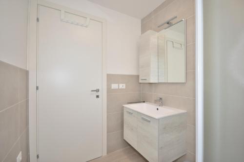 een witte badkamer met een wastafel en een spiegel bij Condominio Aliante in Bibione