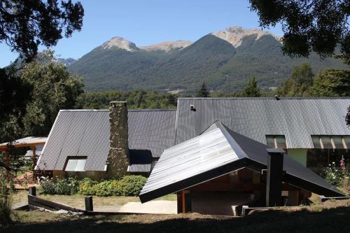una casa con techo con montañas al fondo en Huerta de los Andes - Bed and Breakfast en Villa La Angostura