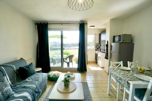 ein Wohnzimmer mit einem Sofa und einem Tisch sowie eine Küche in der Unterkunft La Lézardière *Front de mer* in Ploemeur