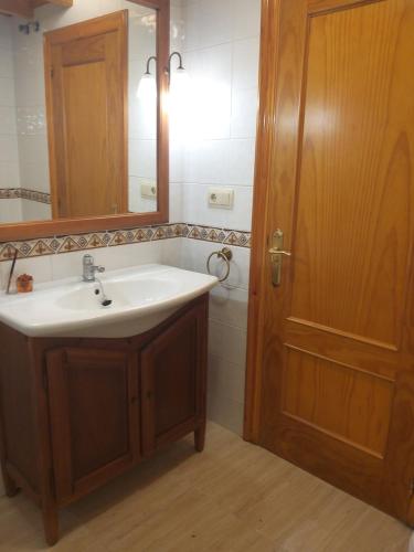 uma casa de banho com um lavatório, um espelho e uma porta em Apartamento con pequeño jardín en el centro em Ferrol