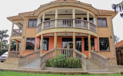 uma grande casa com uma grande varanda na parte da frente em Da Rose Guest House and SPA em Kampala