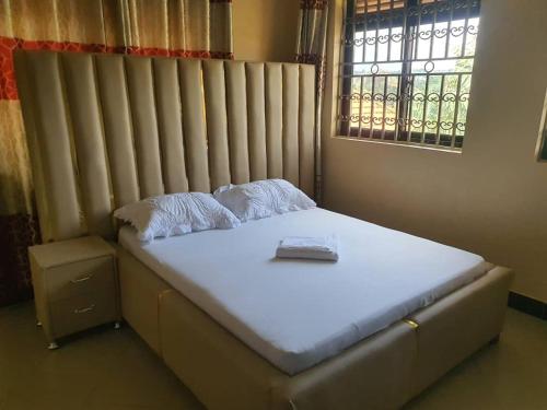 uma cama num quarto ao lado de uma janela em Da Rose Guest House and SPA em Kampala