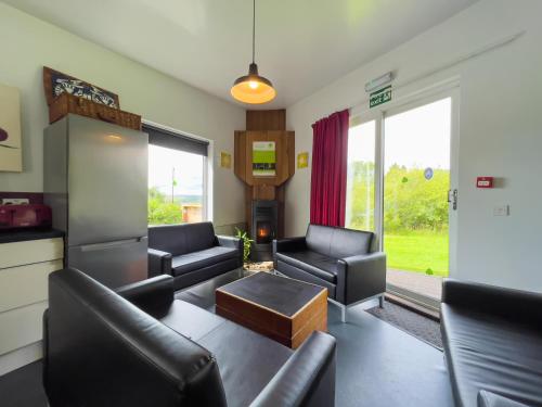 a living room with black leather furniture and a tv at Tarset Tor Bunkhouse in Hexham