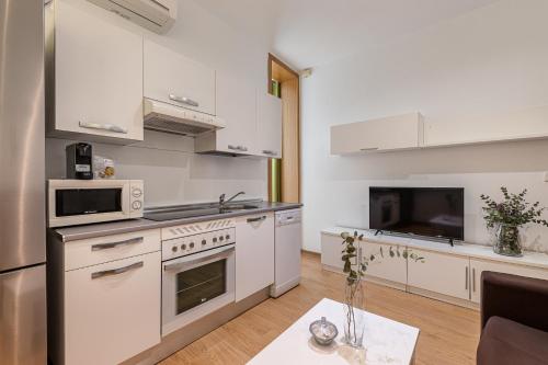 cocina blanca con electrodomésticos blancos y mesa en BNBHolder Apartamentos en Sol Confort 4, en Madrid