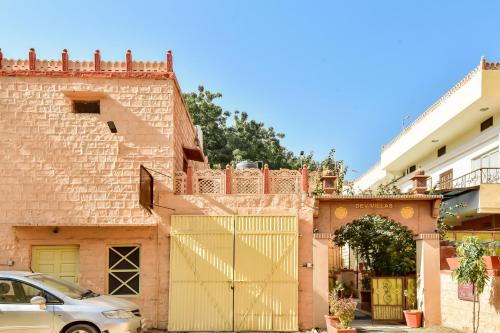 a building with a gate and a car parked in front at Super OYO Dev Villas Guest House in Jodhpur