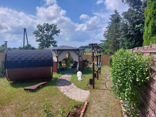 einen Hinterhof mit einem Pavillon und einem Spielplatz in der Unterkunft Całoroczny Dom na wsi z Sauna I Jacuzzi in Płużnica