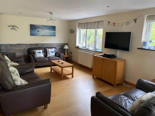 a living room with couches and a flat screen tv at Karrek View - Trebarwith Strand (Sleeps 8-10) in Treknow