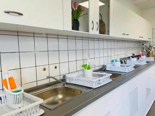 a kitchen counter with white dish drying racks and a sink at Boardinghouse Kevelaer in Kevelaer
