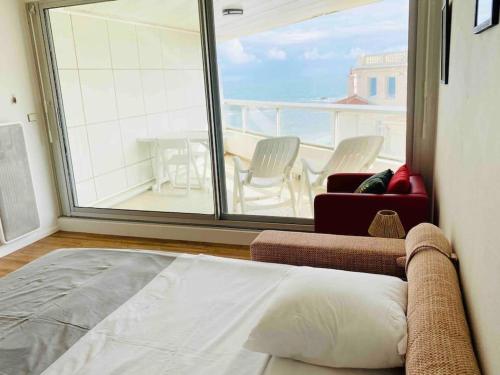 ein Schlafzimmer mit einem Bett und ein großes Fenster mit einem Tisch und Stühlen in der Unterkunft Studio front de mer Biarritz - Spa & Thalasso in Biarritz