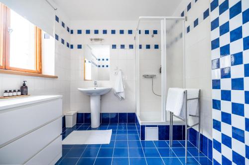 y baño azul y blanco con lavabo y ducha. en Chalupa pod Maralákem, en Čeladná