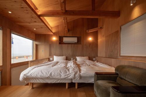 a bedroom with a bed and a couch and a window at OH!TOMARI in Nanao