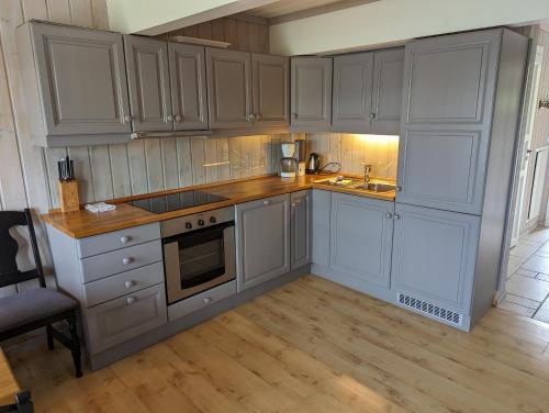 a kitchen with white cabinets and a sink and a stove at Grønolen Fjellgard in Beitostøl