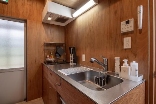 七尾的住宿－OH!TOMARI，厨房设有不锈钢水槽和木墙