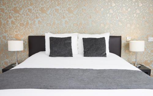 a bedroom with a bed with pillows and two lamps at Chequers Inn by Greene King Inns in Maresfield