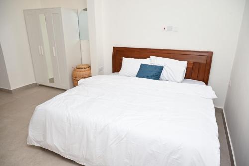 a white bed with a wooden headboard and white pillows at Lokko Serene in Accra