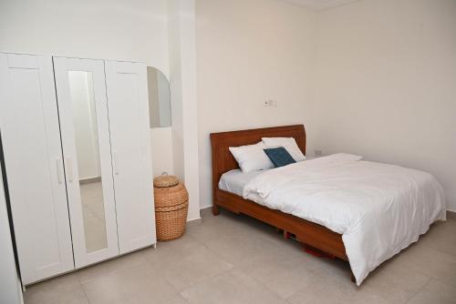 a white bedroom with a bed and a mirror at Lokko Serene in Accra