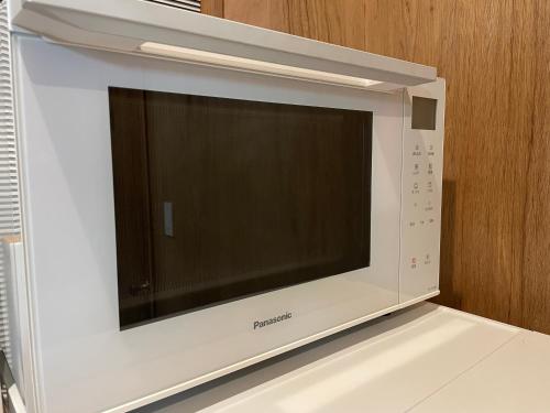 a white microwave oven with a large screen at 一棟貸し宿OH!TOMARI-バレルサウナの有無選択できますo in Nanao