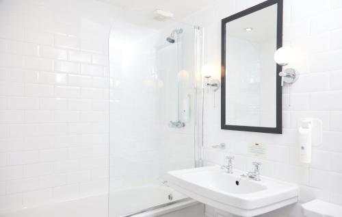 Baño blanco con lavabo y espejo en Chequers Inn by Greene King Inns, en Maresfield