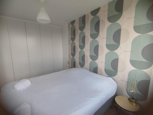 een kleine slaapkamer met een wit bed en een muur met patronen bij Arandes in Dijon