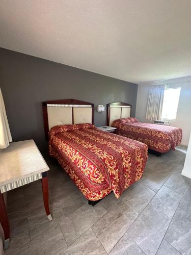 um quarto de hotel com duas camas e uma mesa em Budget Inn Express em Daytona Beach