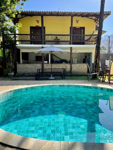a swimming pool in front of a house at Maui Suítes e Chalés in Arraial d'Ajuda