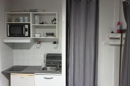 een keuken met een wastafel en een magnetron bij House with outbuilding near Stade de France in Épinay-sur-Seine