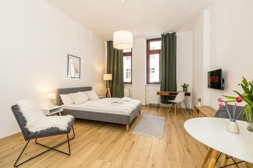 a living room with a bed and a table and chairs at Ruhige und stilvolle Wohnung am Clara-Zetkin-Park in Leipzig