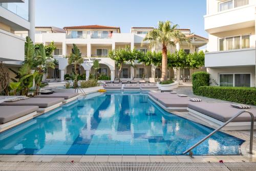 uma piscina com espreguiçadeiras e um edifício em Dimitrios Village Beach Resort em Retimno