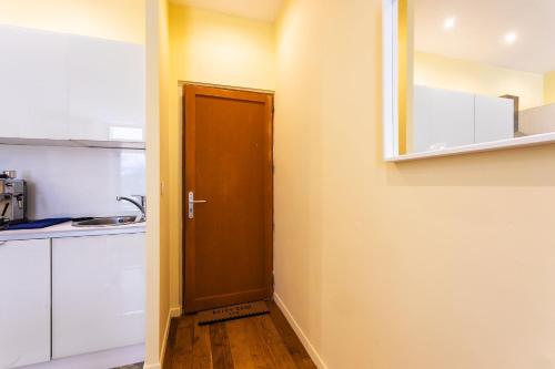 une cuisine avec des placards blancs et une porte marron dans l'établissement LE ST FRANCOIS AP4368 By Riviera Holiday Homes, à Nice