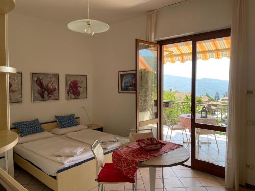 a bedroom with a bed and a table and a balcony at Residence Mirabel in Tignale