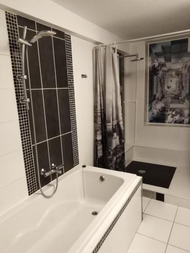 une salle de bain blanche avec une baignoire et une douche dans l'établissement Appart du 21, à Sainte-Marie-aux-Mines