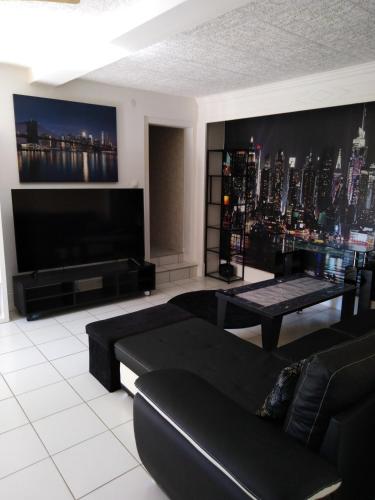 un salon avec un canapé noir et une grande télévision dans l'établissement Appart du 21, à Sainte-Marie-aux-Mines