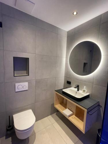 a bathroom with a sink and a toilet and a mirror at Rest Apartments & Suiten in Mauterndorf