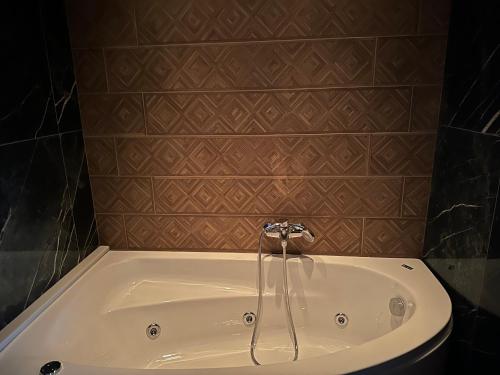 a bath tub with a faucet in a bathroom at Loutraki Flamingo Feather in Loutraki