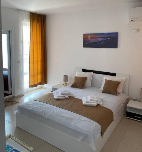 a bedroom with a large bed with two towels on it at Хотел CANAVAN'S - beach in 2 minutes, free parking and WiFi in Ravda